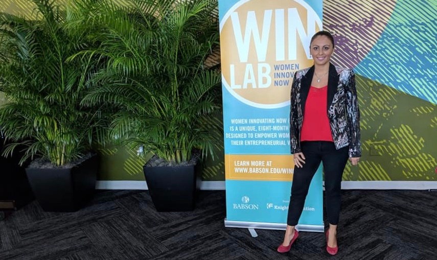 Liz Pasillas next to a WIN Lab Women Innovating Now banner
